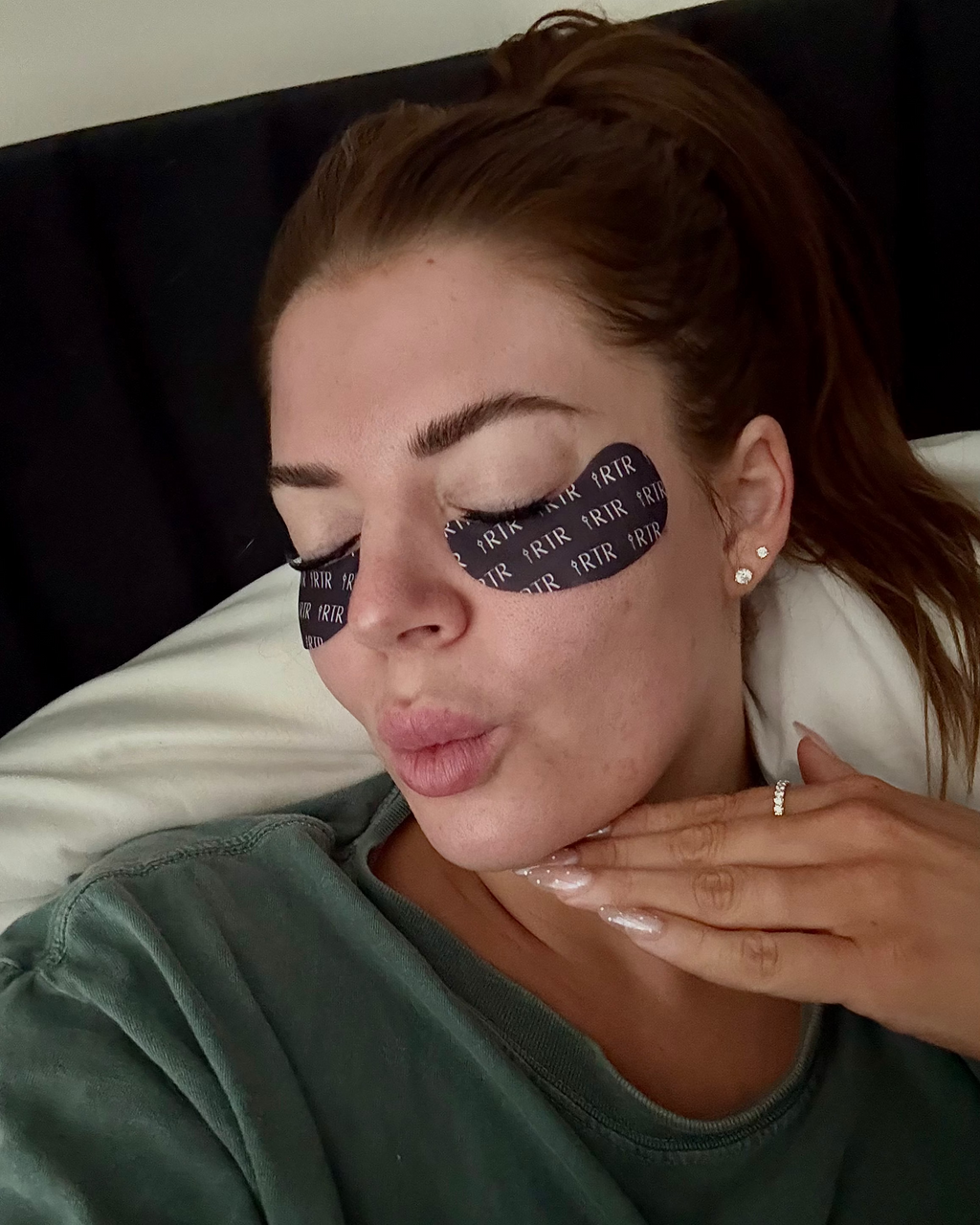 A woman lying down with the RTR eye patches and resting on a white pillow.
